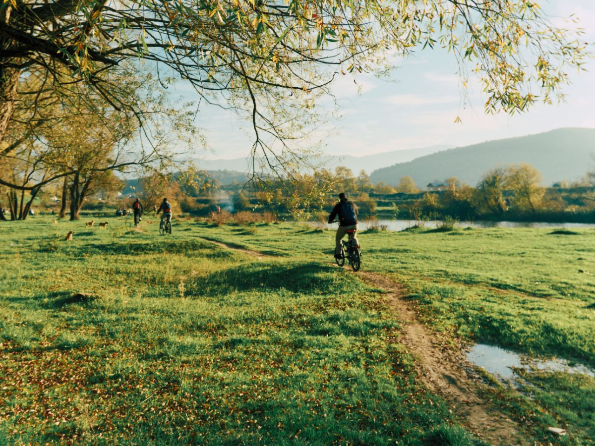Radfahrer auf einem Wiesenweg am Fluss