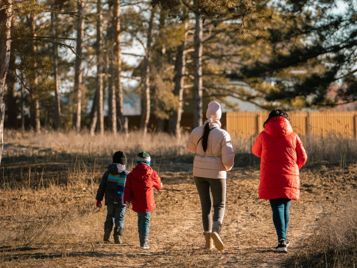 Familie mit Kindern auf einem Weg unter Kiefern